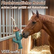 Ein Pferd in einer Box beschnuppert das VOSS.farming Pferdespielzeug Beschäftigung Kaktus 36cm, das in Form eines Lederkaktus von VOSS.farming an der Wand hängt.