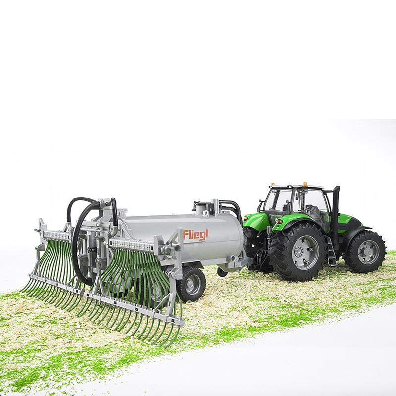 Ein grüner Traktor zieht den BRUDER Fliegl Fassanhänger Spielzeug-Treckeranhänger (1:16, mit Schleppschlauchverteiler) von BRUDER über ein weiß-grünes Feld.