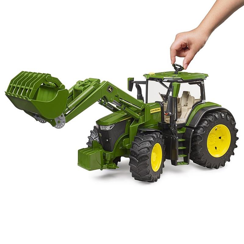Eine Hand berührt das Dach eines BRUDER John Deere 7R 350 Traktors mit Frontlader im Maßstab 1:16, mit zu öffnender Motorhaube und Türen, geeignet für Kinder ab 3 Jahren.